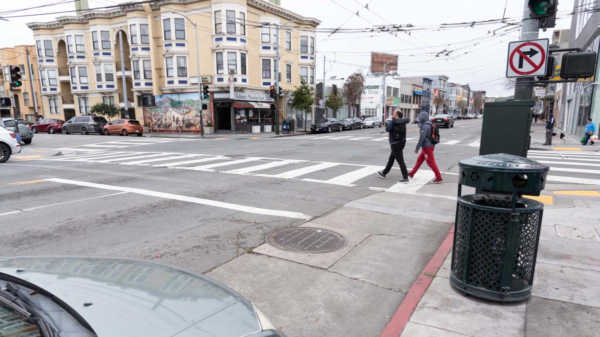 People crossing the street by a red curb